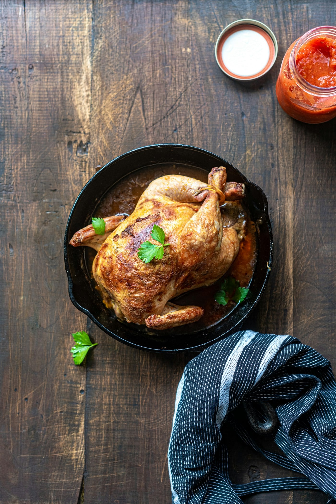 A roast chicken in a skillet, finished with herbs